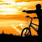 Crianças no pôr do sol numa bicicleta
